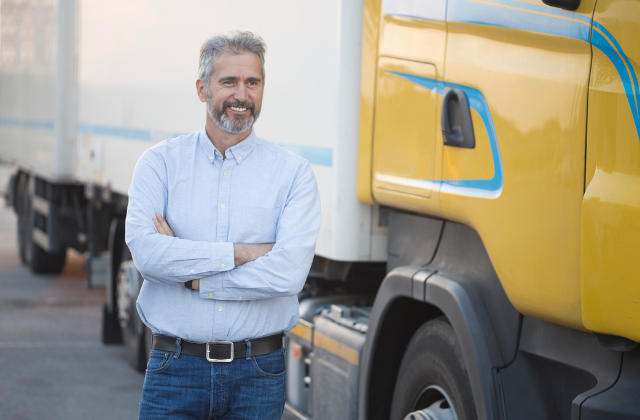 Truck Driver standing in front of yellow semi tractor trailer